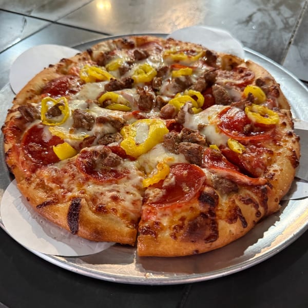 Task Force Pizza Co. pepperoni, sausage, and banana pepper pizza on a metal tray.